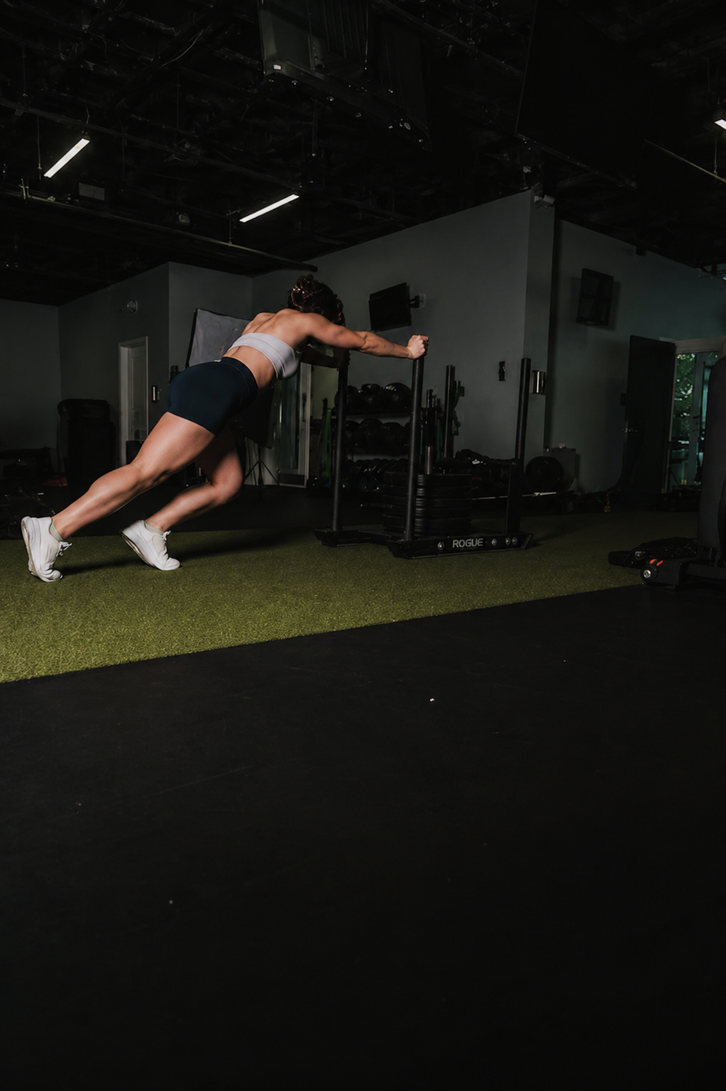 Athlete pushing a sled across a gym floor.